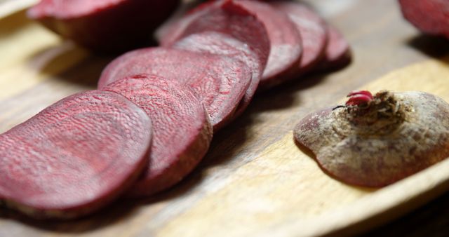 Sliced beetroot is arranged on a wooden cutting board, showcasing the vibrant red hues of the fresh vegetable. Beetroots are known for their nutritional benefits and are often used in healthy cooking.