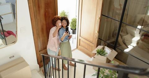 Couple smiling and posing for selfie at open front door during moving day