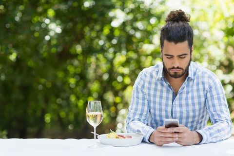 Man Relaxing with Smartphone at Outdoor Dining Table