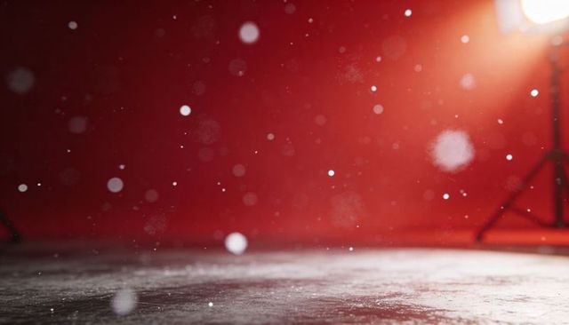 Warm spotlight highlighting floating dust particles over textured concrete floor with red backdrop