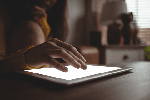 Woman's hand using transparent tablet indoors on wooden table