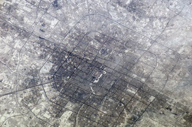 A detailed aerial view of Beijing, China's vast cityscape as captured from the International Space Station. The image highlights the intricate network of streets and urban planning distinct to Beijing. An ideal shot for studies in geography, urban development, or even promotional material for space exploration and city infrastructure. This can be used in educational material, travel articles, or documentaries focusing on China's capital city or Earth observation from space.