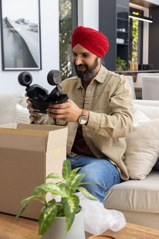 Man unpacking virtual reality headset on sofa at home