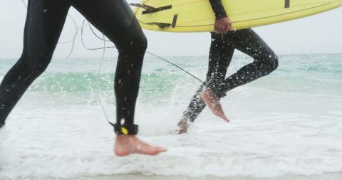 Surfers Running with Surfboards Along the Sandy Beach