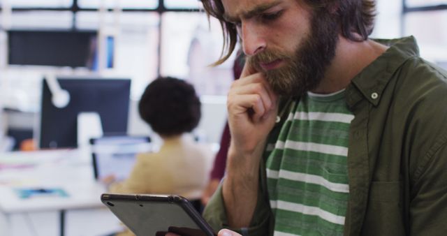 Pensive Man Touching Chin While Reading on Tablet in Office - Download Free Stock Images Pikwizard.com