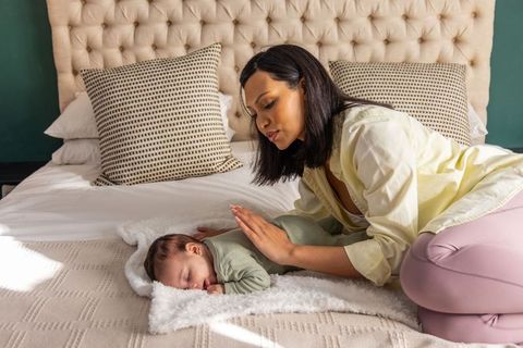 African american mother soothing sleeping newborn on bed, nurturing caregiving moment