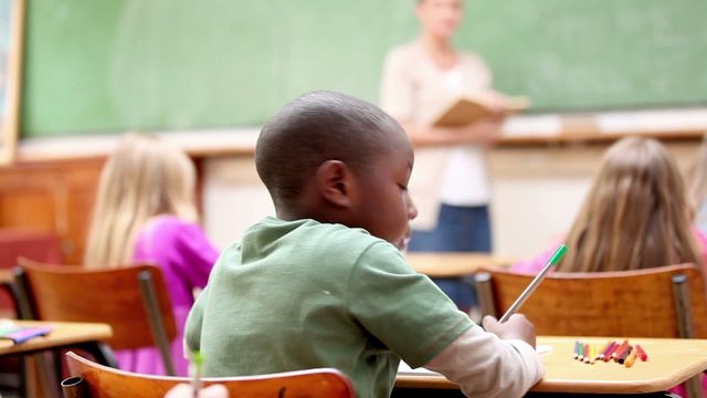 Young students focused in a classroom setting, surrounded by educational materials. Ideal for showcasing concepts related to education, teaching methodologies, and childhood learning. Useful for articles, blogs, and social media posts about the importance of early education and school environments.