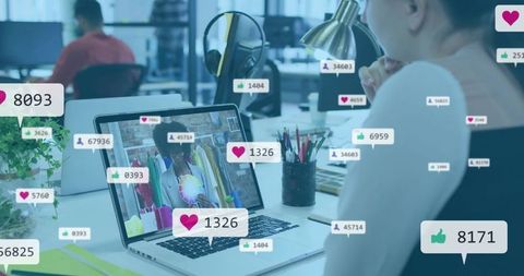 Watching woman following livestream on laptop in coworking office with social engagement icons