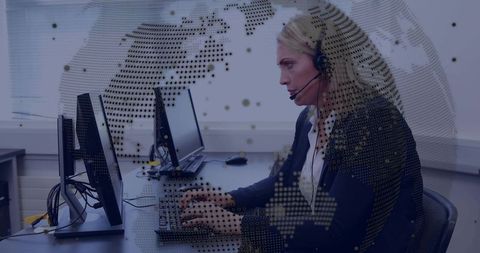 Woman typing at multi-monitor workstation with headset and digital globe overlay