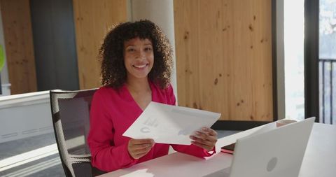 Businesswoman Smiling While Holding Presentation in Modern Office