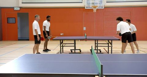 Friends engaging in energetic table tennis match in gym