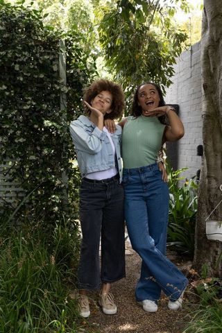 Playful african american friends posing in lush backyard wearing denim casual outfits