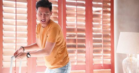 Happy Man Packing Suitcase for Vacation at Home