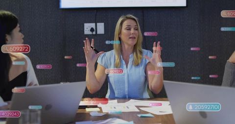 Leading strategic meeting while gesturing and presenting in modern boardroom with laptops