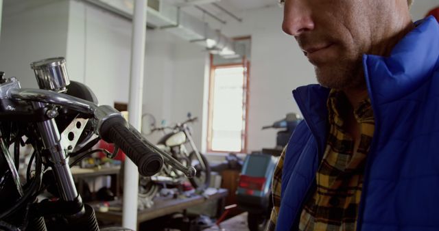 Man Inspecting Motorcycle in Workshop - Download Free Stock Images Pikwizard.com