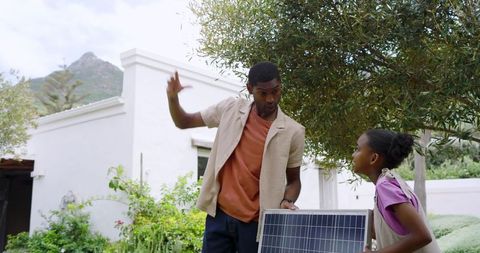 Father and daughter with solar panel learning eco-friendliness