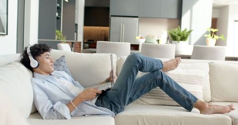 Relaxed Man Listening to Music While Browsing Laptop at Home