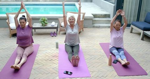 Senior women stretching on poolside yoga mats practicing wellness and gentle exercise