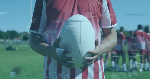 Rugby player holding ball with digital hud overlay on grassy training pitch