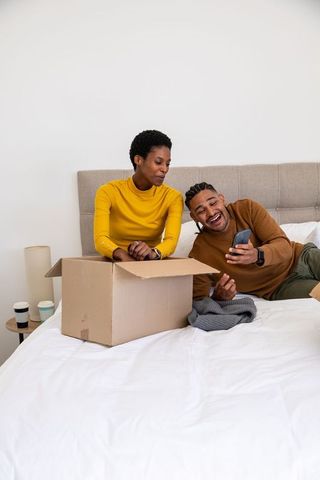 Couple enjoying unboxing together on bed with smartphone