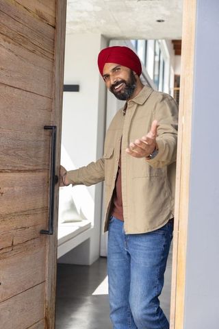 Welcoming man in modern home entry inviting with warm gesture