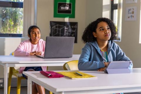 Preteen girls using tablet and laptop in classroom learning with digital technology
