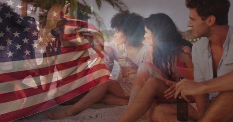 Group Enjoying Beach Party with American Flag Overlay at Dusk