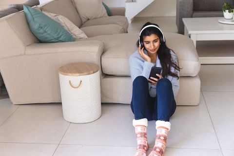 Woman Sitting at Home Listening to Music on Headphones
