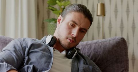 Man with Headphones Relaxing on Couch Using Tablet