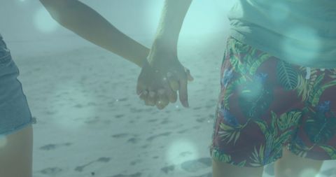 Couple Holding Hands at Beach with Dreamy Blue Bokeh