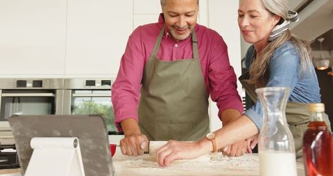 Senior Couple Rolling Dough in Modern Kitchen