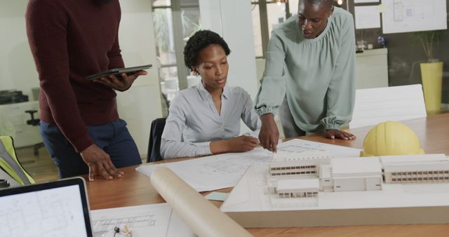 Team of architects collaborating on a building project in a modern office, discussing blueprints and design plans. Ideal for use in articles about architecture, teamwork, professional collaboration, and urban development projects.