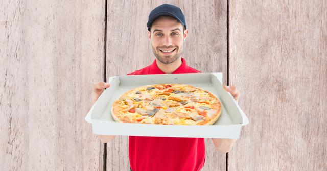 Digital composite of Delivery man showing pizza against wall