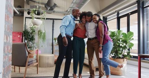 Diverse colleagues sharing warm embrace in modern office