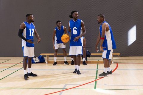 African american basketball teammates strategizing on indoor court holding ball