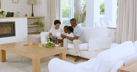 Family Bonding Joyfully on Sofa in Sunlit Living Room
