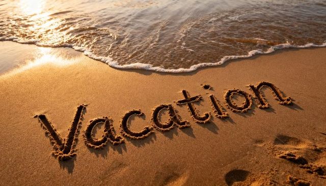 Vacation written in sand on shoreline at golden hour with gentle waves and footprints