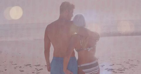 Couple Embracing on Sunlit Beach During Romantic Sunset