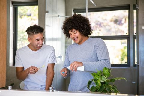 Diverse Friends Brushing Teeth Laughing in Bathroom