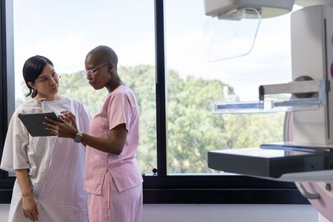 Female clinician consulting patient using tablet during breast imaging appointment