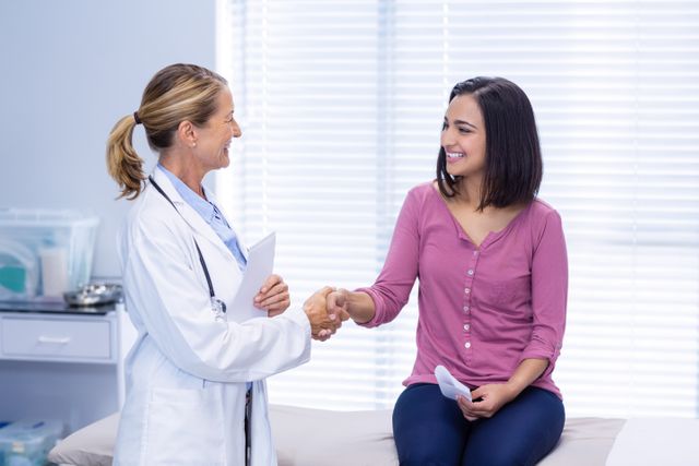 Female doctor shaking hands with patient in clinic. Ideal for illustrating medical consultations, healthcare services, doctor-patient relationships, and professional medical advice. Useful for healthcare websites, medical brochures, and patient care articles.