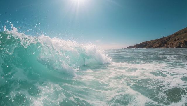 Turquoise ocean wave crashing under sunlight with white foam