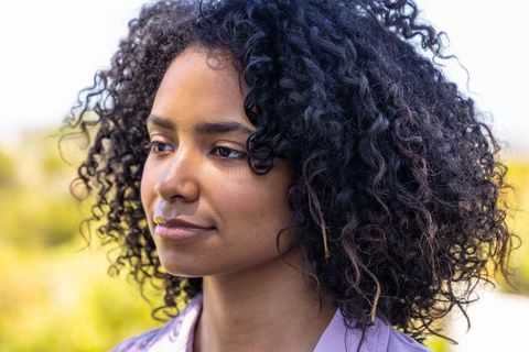 African american woman posing peacefully outdoors with curly hair and natural sunlight