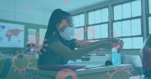 Schoolgirl with face mask using sanitizer in classroom