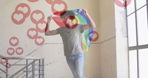 Confident Young Man Celebrating Pride with Vibrant Flag on Staircase