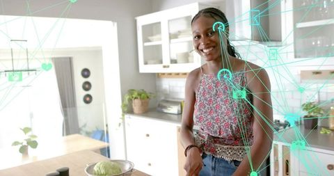 Smiling Woman Slicing Vegetables in Modern Kitchen with Digital Elements