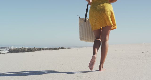 Low section biracial woman walking on beach with bag. Summer, relaxation, vacation, happy time, summer time.