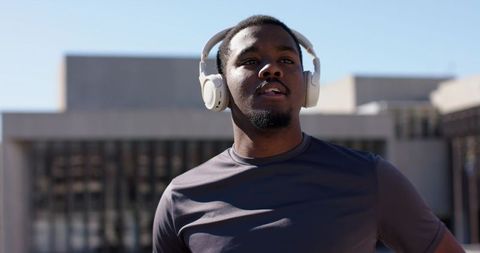 African American man wearing white headphones gazing upward on rooftop