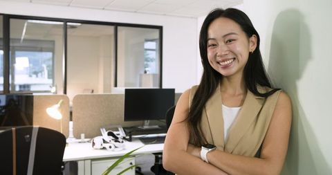 Confident asian businesswoman smiling by desk with vr headset in modern office