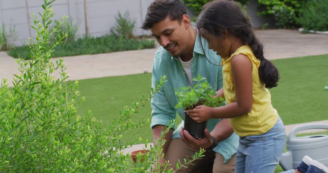 Father assisting daughter in planting seeds in garden. They are engaging in outdoor gardening activity, teaching about nature and environment, and spending quality family time together. Ideal for use in parenting articles, educational content, and promotions about family activities or environmental awareness.